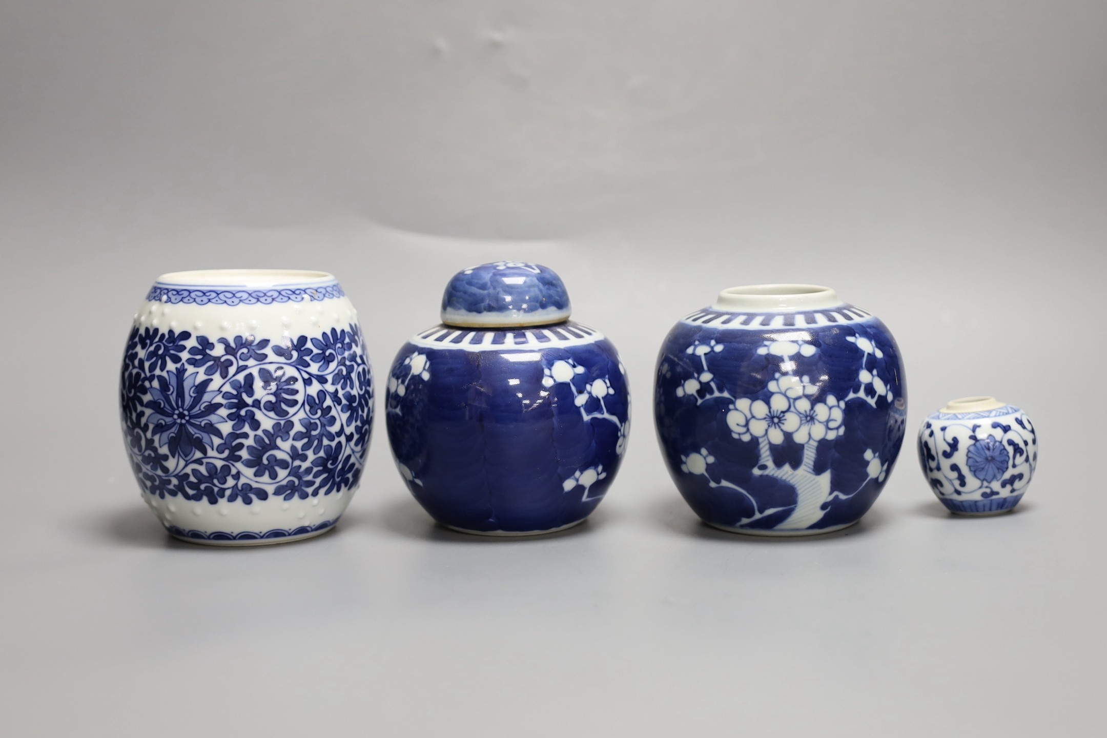 A pair of Chinese blue and white prunus jars, one with cover, a similar smaller jar and a ‘barrel’ jar